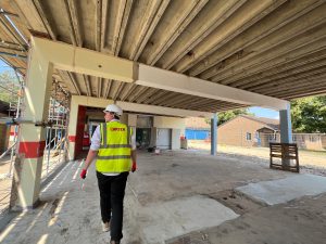 A construction worker in a high‑visibility vest and hard hat walks through the stripped‑back Oswald Building at Abbey College Ramsey during refurbishment works.