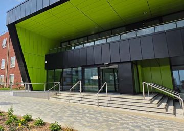 Main entrance to The Vincent Building extension at Cranfield University, featuring distinctive lime green and black rain-screen cladding.